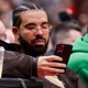 Drake, the rapper, looks at his phone during an NBA game.